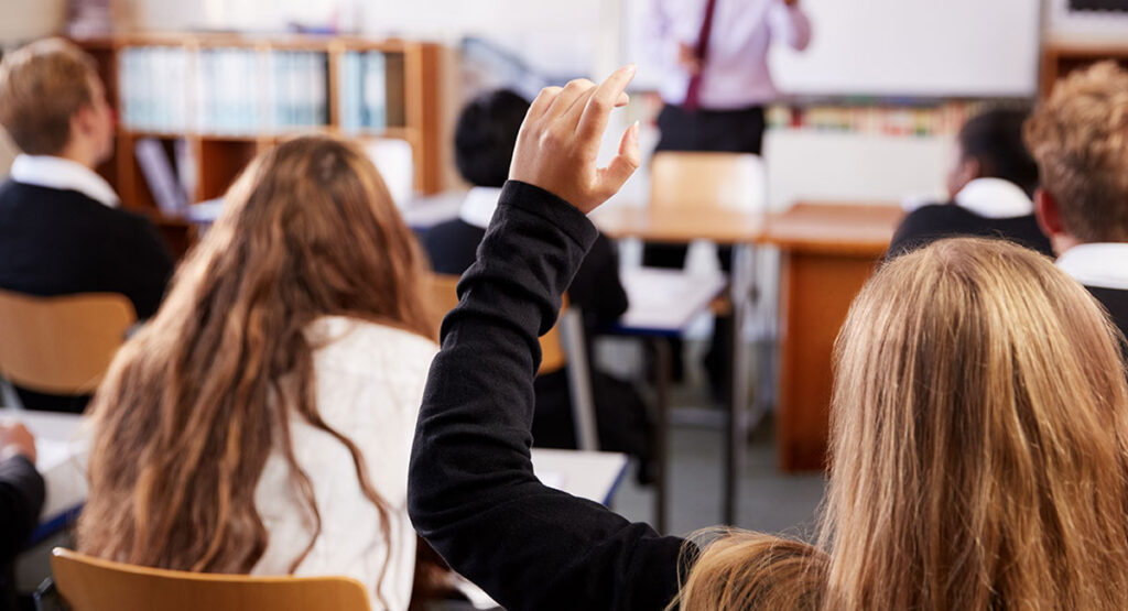 Young people sitting at desks in a school or college