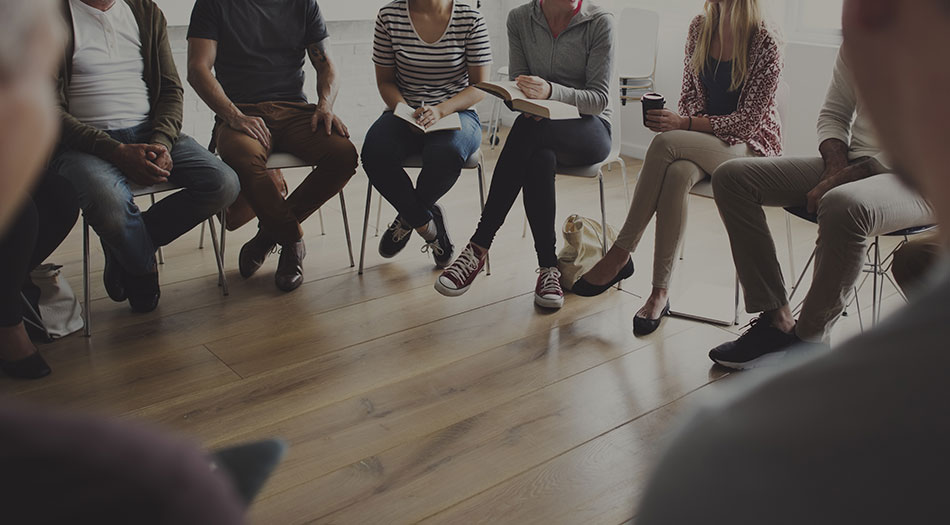 People sitting in a circle of chairs having a meeting